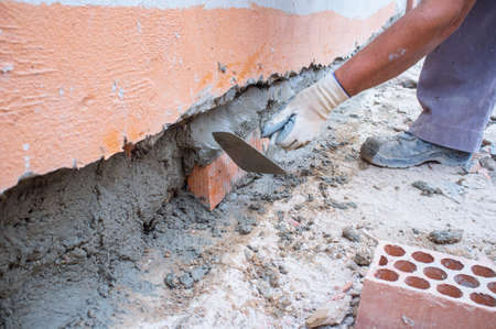 Bricklayer laying brick to cover a hole on wall. closeupの写真素材