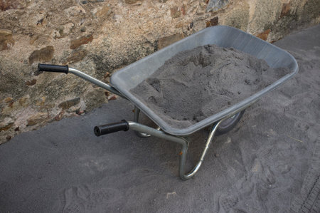 Wheelbarrow loading black topsoil. Construction industry tool