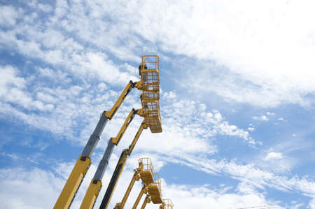 Telescopic booms. Some platforms lifted over blue skyの写真素材