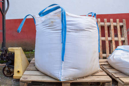 Raffia large sand sack stacked over Hand Pallet Jack Hydraulic Welding Pum. Construction material...
