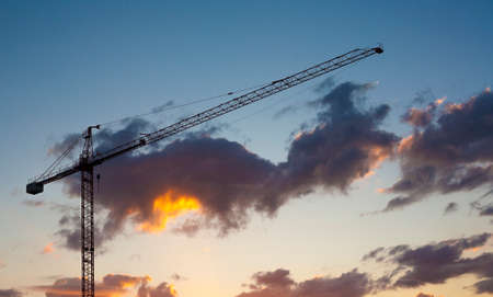 Construction site with crane silhouette at sunset over blue orange sky