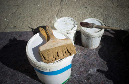 Painter brushes over buckets. Stone granite floor protected with blanketの写真素材