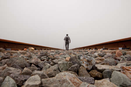 A man walking on the tracks with cane and trekking clothes a dense foggy dayの写真素材