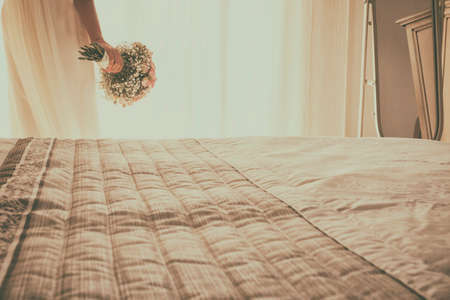 Bride standing in front of the window and holding the bouquet. She waits impatiently the wedding carの写真素材