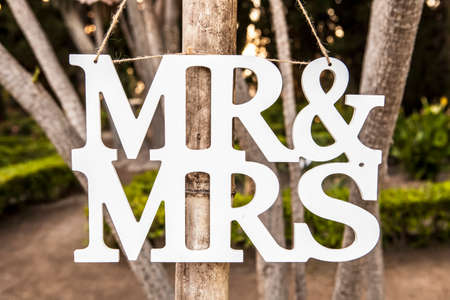Mr and Mrs White Wedding letters hanging sign from wooden pole with garden on backgroundの写真素材