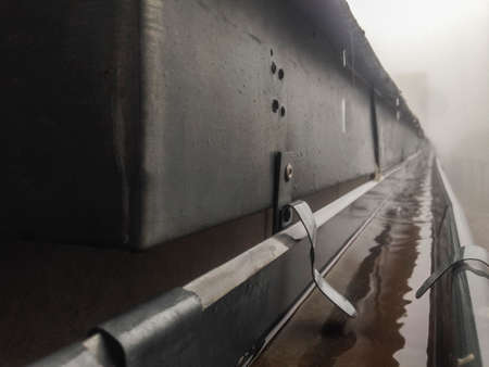 Gutter drainage system on the roof with dripping fog and rain. closeup
