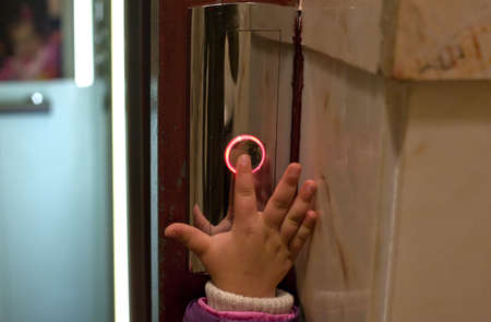 Hand of a toddler in elevator or lift pressing the button to get in