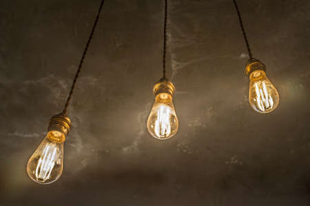 Hanging light bulbs over oxide dark color concrete background. closeup