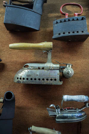 Collection of old metal clothes irons attached to the wall. closeup