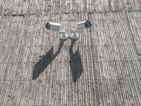 Two security cameras on gray concrete building wallの写真素材