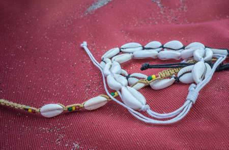 Shell ankle bracelet over red sailcloth fabric. Symbol of summertimeの写真素材