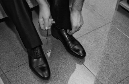 Man's hands lacing up shoes closeup before weddingの写真素材