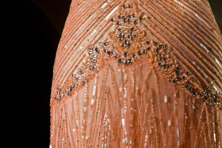 Detail of salmon colored bridesmaid gown with ornaments as rhinestones and sequins
