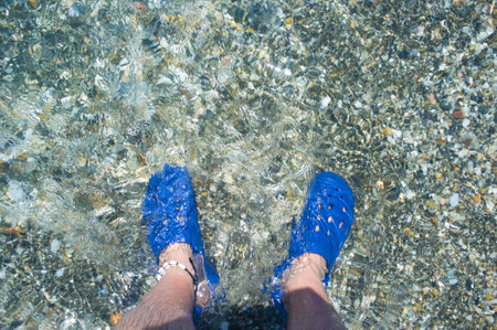 Male wearing blue clogs beside the beach. selective focus