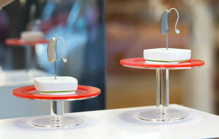 Modern Hearing aid devices displayed on base. closeup