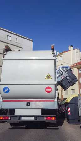 Trash truck collecting urban paper dumpster. Smart hydraulic system rise blue container...