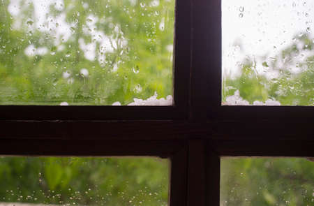 Hail over wooden window frame. Selective focus over green backgroundの写真素材