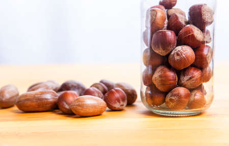 Pecan walnuts and hazelnut on glass jar over wooden surface. Isolated over white backgroundの写真素材