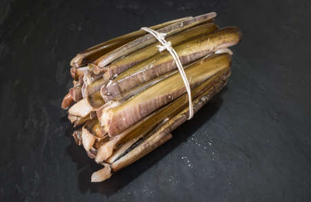 Bundle of razor clams. Isolated over black slate