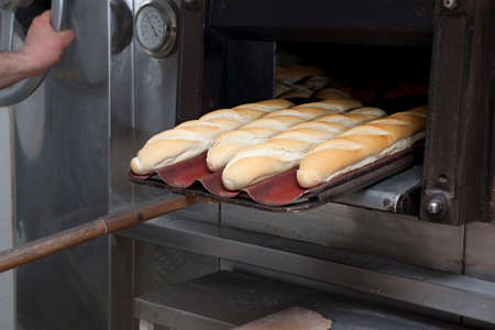 baking peel taking fresh baked bread from oven. Manufacturing process of spanish breadの写真素材