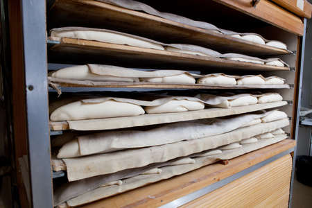 Raw pieces of bread in the fermentation wooden cabinet. Manufacturing process of spanish bread