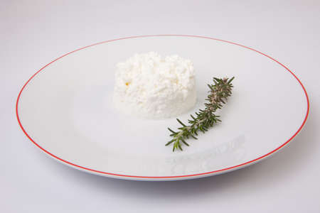 Granulated cottage cheese over plate with a rosemary branch. isolated over white