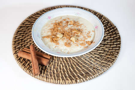 Delicious homemade rice with milk and cinnamon in a china bowl, over natural fiber place matの写真素材
