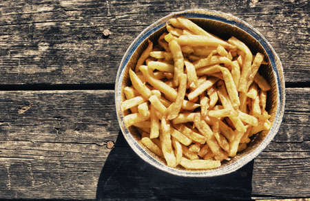 French fries in aluminum foil tray. Served over old wooden picnic tableの写真素材