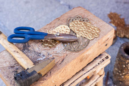 Craftsman bench with tools for engrave hamsa palm-shaped brass amulets