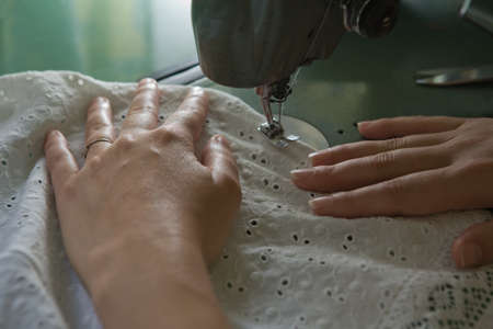 Hands of a dressmaker supporting a cloth while sewing on a sewing machine, Spain