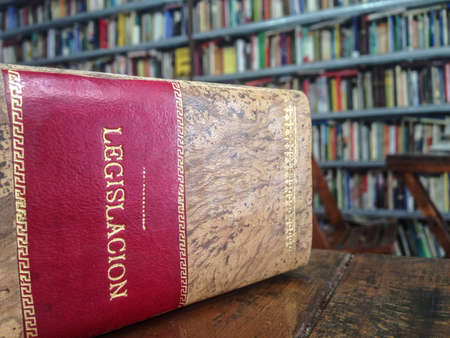Law book in Spanish over table. library shelves background