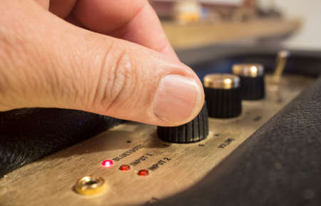 Fingers adjusts fine-tune controls of retro style bluetooth speaker. selective focus