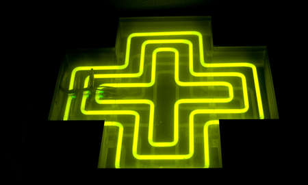 Pharmacy neon green cross sign at nightの写真素材