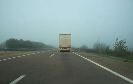 Driving behind a truck under dense fog. Bad weather driving concept