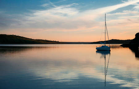 Sailboat anchored in the middle of Alange Reservoir, Spain. sunset time