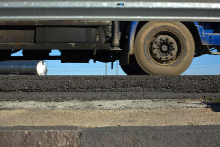 Truck wheels between dark asphalt road and rail guards. motion shotの写真素材
