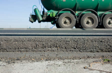 Truck wheels between dark asphalt road and rail guards. motion shotの写真素材