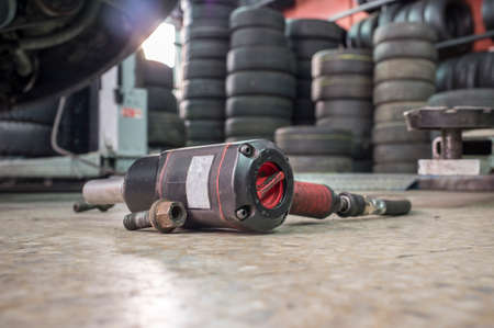 Pneumatic wrench screwing mechanic tool and knots with no wheel car at bottom