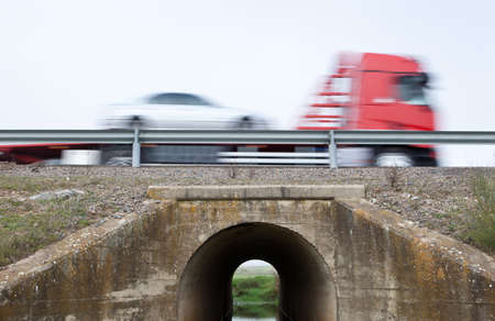 Truck transports cars in motion crossing a canal bridge