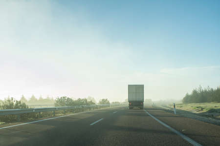 Driving behind a truck under morning haze. Bad weather driving concept