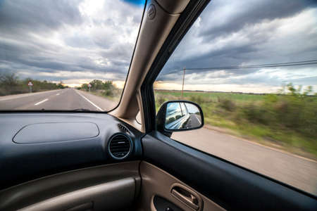 Driving under stormy sky. View from inside the carの写真素材