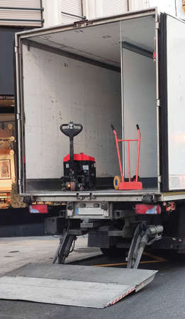 Semi-trailer truck unloading goods at downtown. The truck is equipped with lift ramp