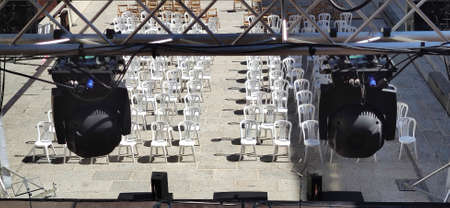 Spot lights structure over white plastic chairs for audience. Summer concerts in the city conceptの写真素材