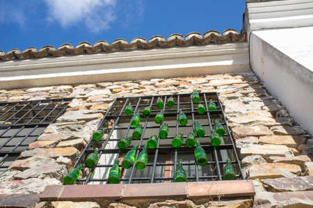 Rural residence house window decorated with hanging green glass bottles. Low angle viewの写真素材