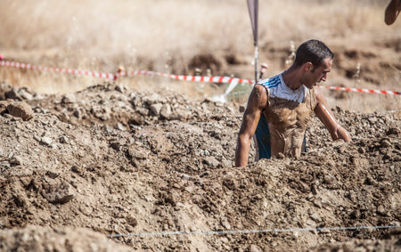 Merida, Spain - Sept 11th, 2022: FarinatoRace Merida 2022. Toughest obstacle course in the world. Trench flooded with barbed wireのeditorial素材