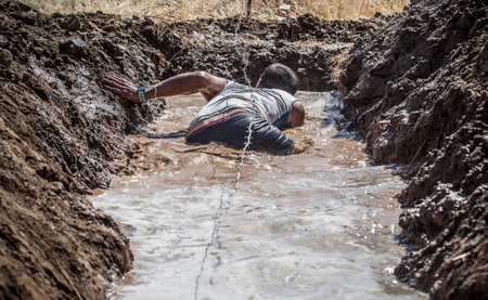 Merida, Spain - Sept 11th, 2022: FarinatoRace Merida 2022. Toughest obstacle course in the world. Trench flooded with barbed wireのeditorial素材