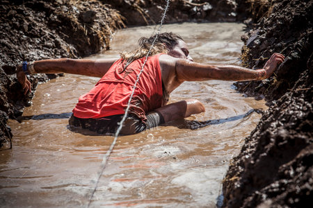 Merida, Spain - Sept 11th, 2022: FarinatoRace Merida 2022. Toughest obstacle course in the world. Trench flooded with barbed wireのeditorial素材