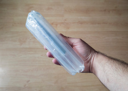 Hand holds a product wrapped with inflatable packaging columns bags. Wooden floor backgroundの写真素材