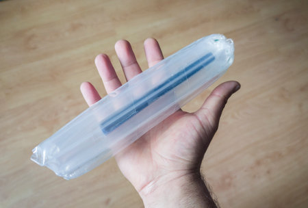 Hand holds a product wrapped with inflatable packaging columns bags. Wooden floor background