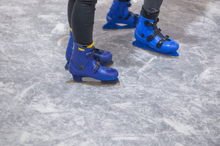 Children enjoy skating on ice. Blue ice skates detail